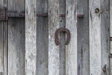 Symbol of success. A metal horseshoe hangs at natural wood door.