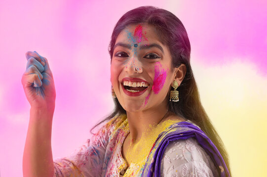A YOUNG WOMAN READY TO THROW GULAL DURING HOLI	