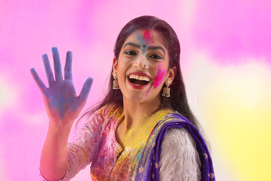 A HAPPY YOUNG WOMAN SHOWING COLOUR FILLED HANDS ON CAMERA