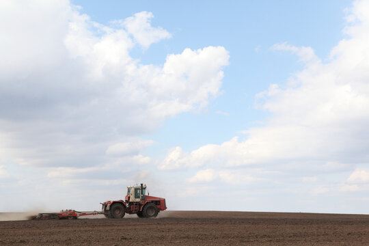 Tractor plows land on spring Russian agricultural field in Ivanovo region, Russia. Agriculture. Farmer is using farming machinery (tractor) for planting process