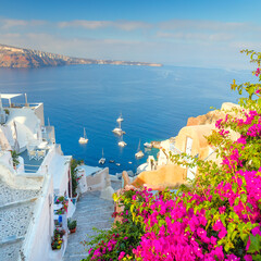 Old street with flowers, traditional Greek houses and a staircase to the sea, Santorini, Greece