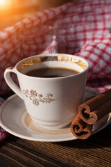 A cup of aromatic black coffee and coffee beans on the table and cinnamon sticks. Morning espresso coffee for breakfast in a beautiful white cup.