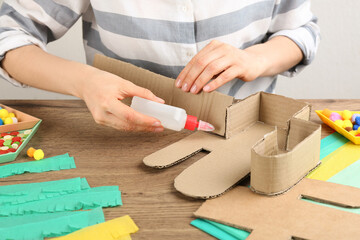 Woman making cardboard cactus at wooden table, closeup. Pinata DIY
