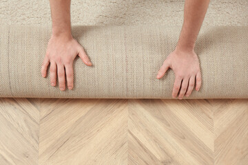 Man rolling out new carpet flooring indoors, top view. Space for text