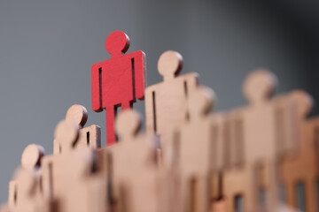 Red wooden figurine standing above others closeup. Leadership skills concept