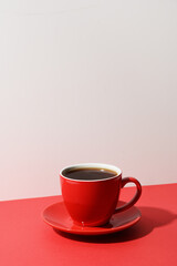 Obraz na płótnie Canvas Red cup of coffee and beans on color white and red background. Vertical format with negative space.