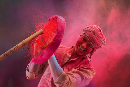A HAPPY YOUNG MAN SHIELDING HIMSELF FROM STICK WHILE PLAYING HOLI	
