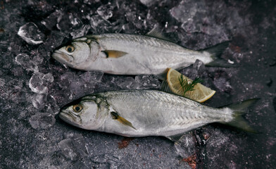 Whole uncooked fish with lemon slice on table