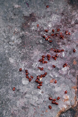 Fresh pomegranate seeds between ice cubes on table