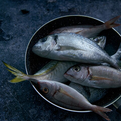Assorted uncooked fish in bowl on table