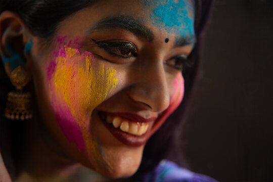 SIDE SHOT OF A HAPPY YOUNG WOMAN WITH GULAL ON HER FACE	