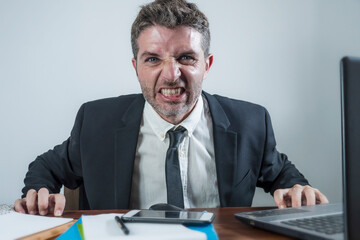 upset and angry businessman at computer desk in office- unhappy man working frustrated suffering stress as employee of corporate business complaining in rage