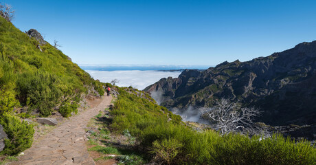 Fototapeta na wymiar Girl walks along the trail. Beautiful mountain landscape. Portugal, Madeira, View of the mountains and Parking PR1.2 Achada do Teixeira near Arieiro peak - the highest point of Madeira island.