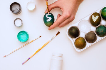Young man painting Easter eggs. Flat lay, view. White background