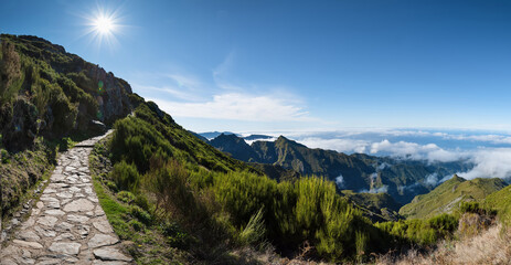 Above the clouds on a mountain trail. Colorful mist in valley. Trekking from Pico do Arieiro to...