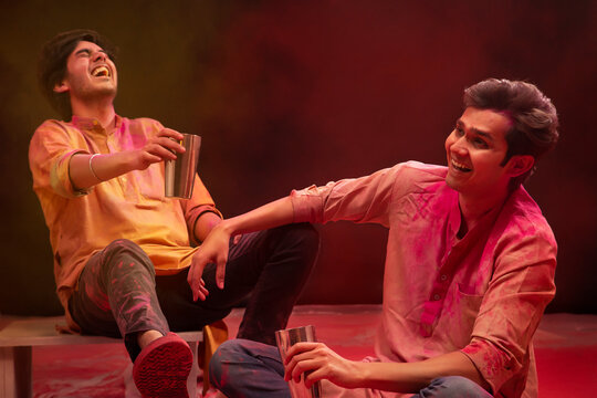 TWO HAPPY FRIENDS LAUGHING TOGETHER WHILE DRINKING BHANG ON HOLI FESTIVAL	