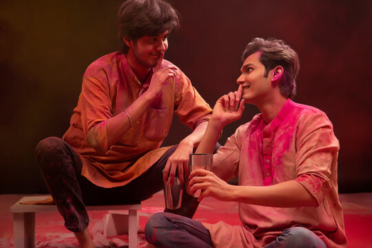 TWO FRIENDS GESTURING EACH OTHER PLAYFULLY WHILE DRINKING BHANG ON HOLI	