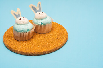 Easter cupcakes on a cork stand. Blue background. Minimalistic composition