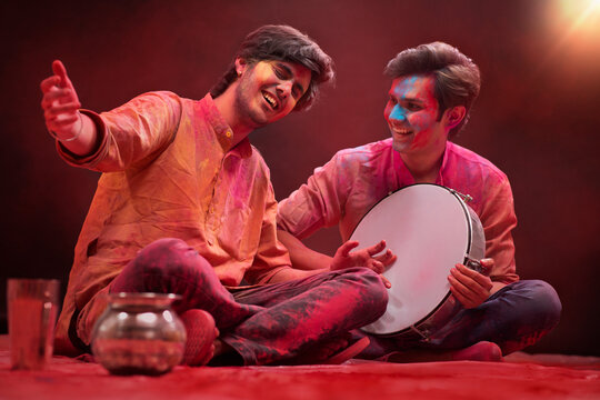 TWO YOUNG MEN SINGING AND PLAYING DAFLI DURING HOLI CELEBRATIONS	