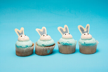 Four Easter muffins on blue background. Minimalistic composition, place for text