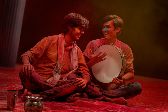 TWO HAPPY MEN LOOKING AT EACH OTHER WHILE PLAYING DAFLI AND CELEBRATING HOLI	
