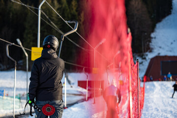 A man in a black jacket, a skier taking a ski lift to the top of the slope.