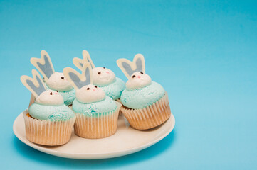 Bunch of cupcakes on a plate. Blue background. Minimalistic composition. Easter concept