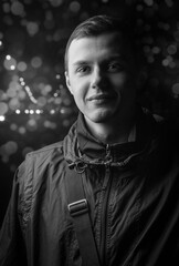 Black-white portrait of a guy in a jacket on a background with bokeh