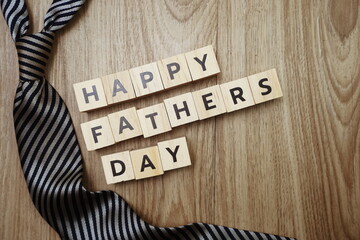 Happy Father's Day alphabet letters with necktie gift box and red heart fluffy on wooden background