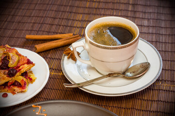 Still life - a hot cup of black coffee, homemade cookies with fruit on a bamboo mat