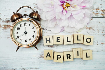 Hello April with alarm clock on wooden background