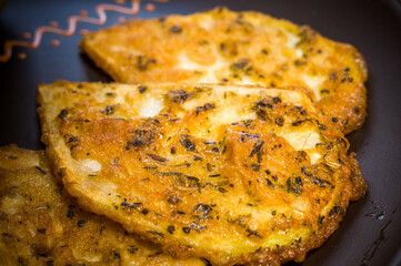 Vegetarian food - celery tuber slices fried in batter in a ceramic plate on a wooden table, close up