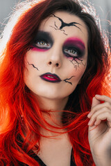 European girl with Halloween makeup under the skull, zombie. Red hair and bright makeup