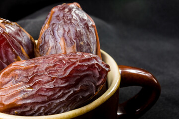 Big luxury dried date fruit in bowls on the dark surface, kurma ramadan kareem concept, close up.
