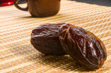 Big luxury dried date fruit on the bamboo mat, kurma ramadan kareem concept, close up.