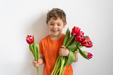 Cheerful happy child with tulips flower bouquet. Smiling little boy on white background.