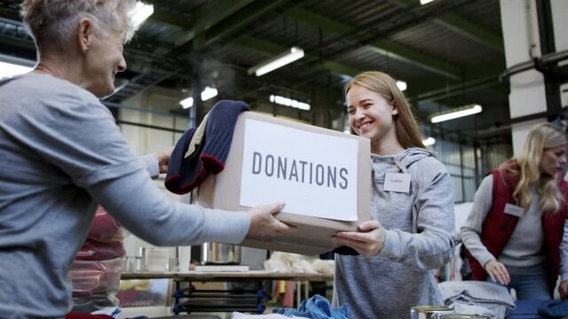 Volunteers sorting out donated clothes in community charity donation center, coronavirus concept.