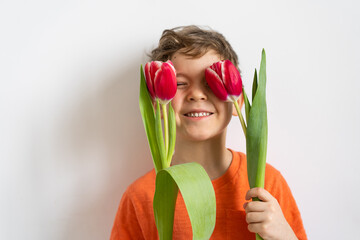 Cheerful happy child with tulips flower bouquet. Smiling little boy on white background.
