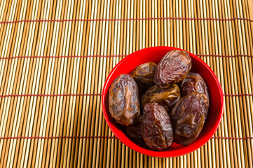 Big luxury dried date fruit in bowls on the bamboo mat, kurma ramadan kareem concept, close up.