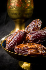 Big luxury dried date fruit in bowls on the dark surface, kurma ramadan kareem concept, close up.