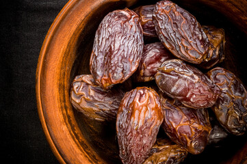 Big luxury dried date fruit in bowls on the dark surface, kurma ramadan kareem concept, close up.