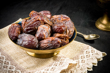 Big luxury dried date fruit in bowls on a linen napkin, kurma ramadan kareem concept, close up.