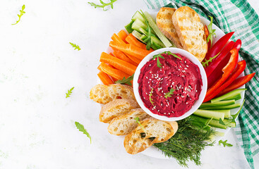 Roasted beet hummus with toast and vegetables on a light background. Beetroot hummus. Top view, above, copy space