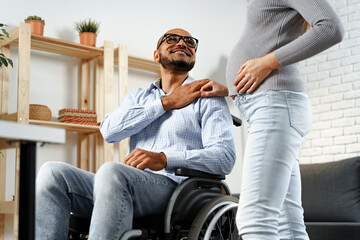 Fototapeta premium Pregnant woman holding a hand of her disabled husband sitting in a wheelchair