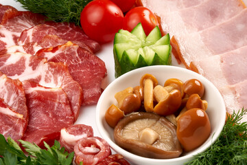 Close-up of pickled mushrooms in a plate with ham on the table.