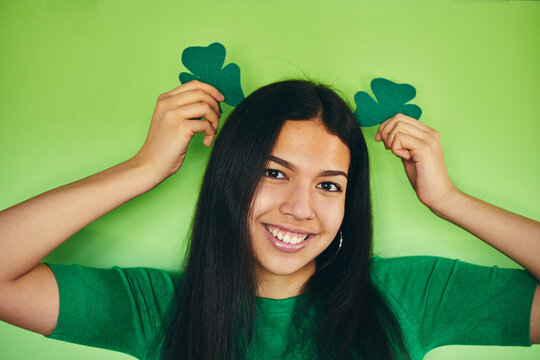 Modern girl holding a shamrock on an isolated green background. Happy St Patrick's day.