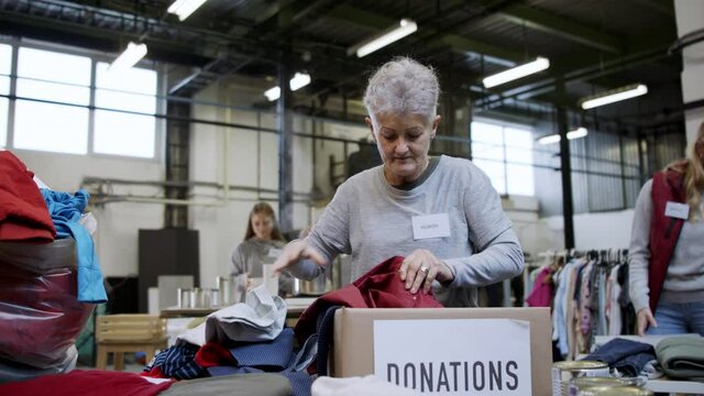 Volunteers sorting out donated clothes in community charity donation center, coronavirus concept.