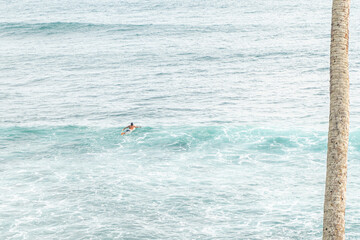 Surfer pośród fal na oceanie na tle zachodu słońca. © insomniafoto