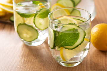 Sassy water or water with cucumber and lemon on wooden table	