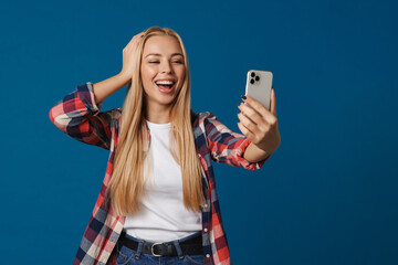 Cheerful beautiful blonde girl taking selfie on smartphone